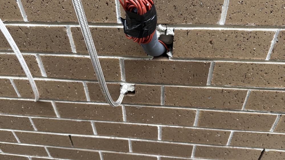Service penetrations through the brick wall left unsealed against the weather, found during a lock-up inspection in Kalkallo